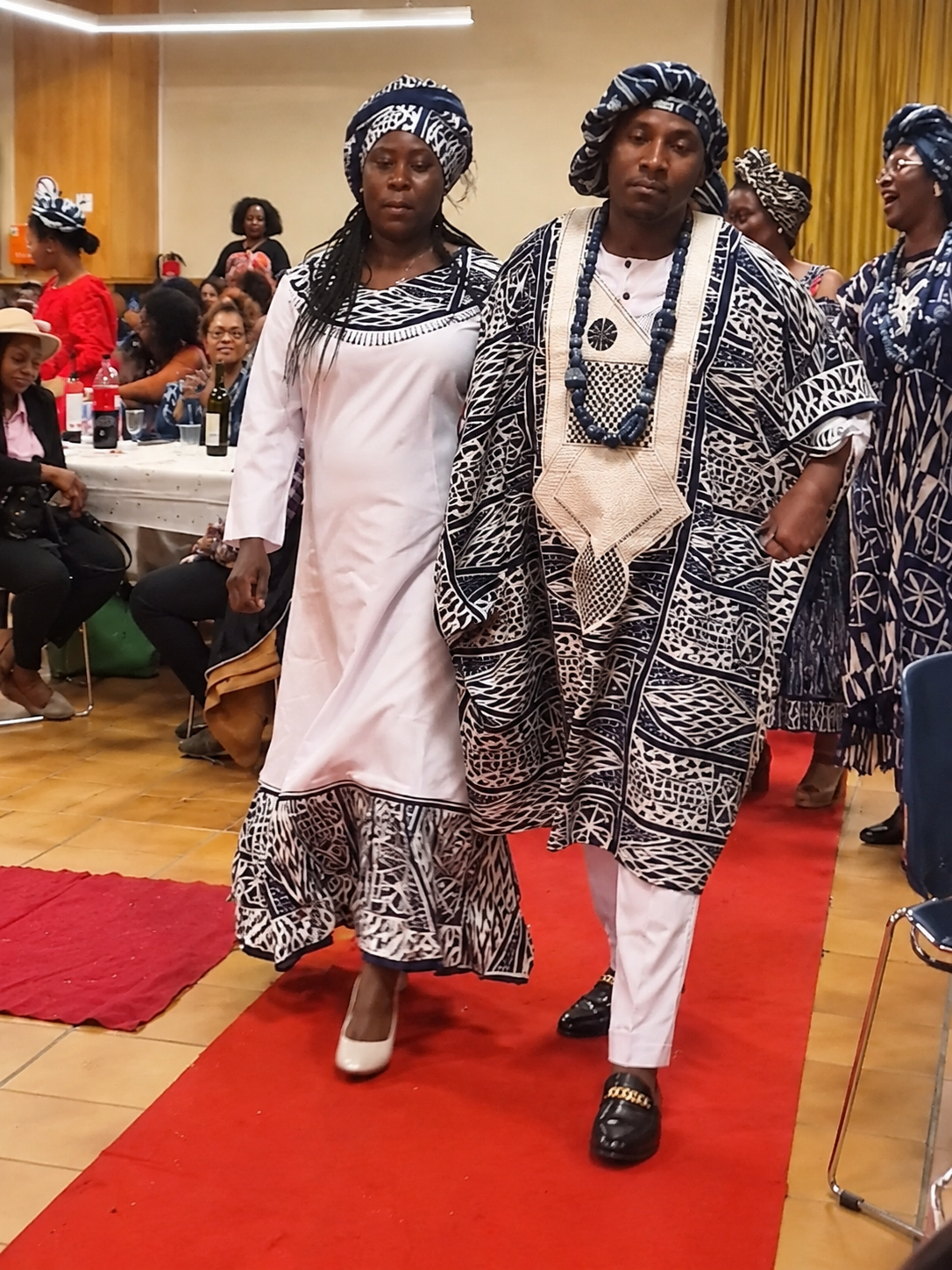 Un couple en tenues traditionnelles noir et blanc avançant sur le tapis rouge